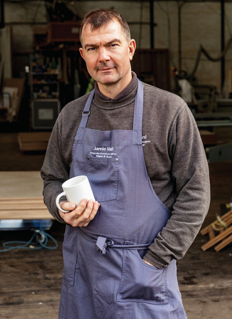 Man in workshop holding a white mug.