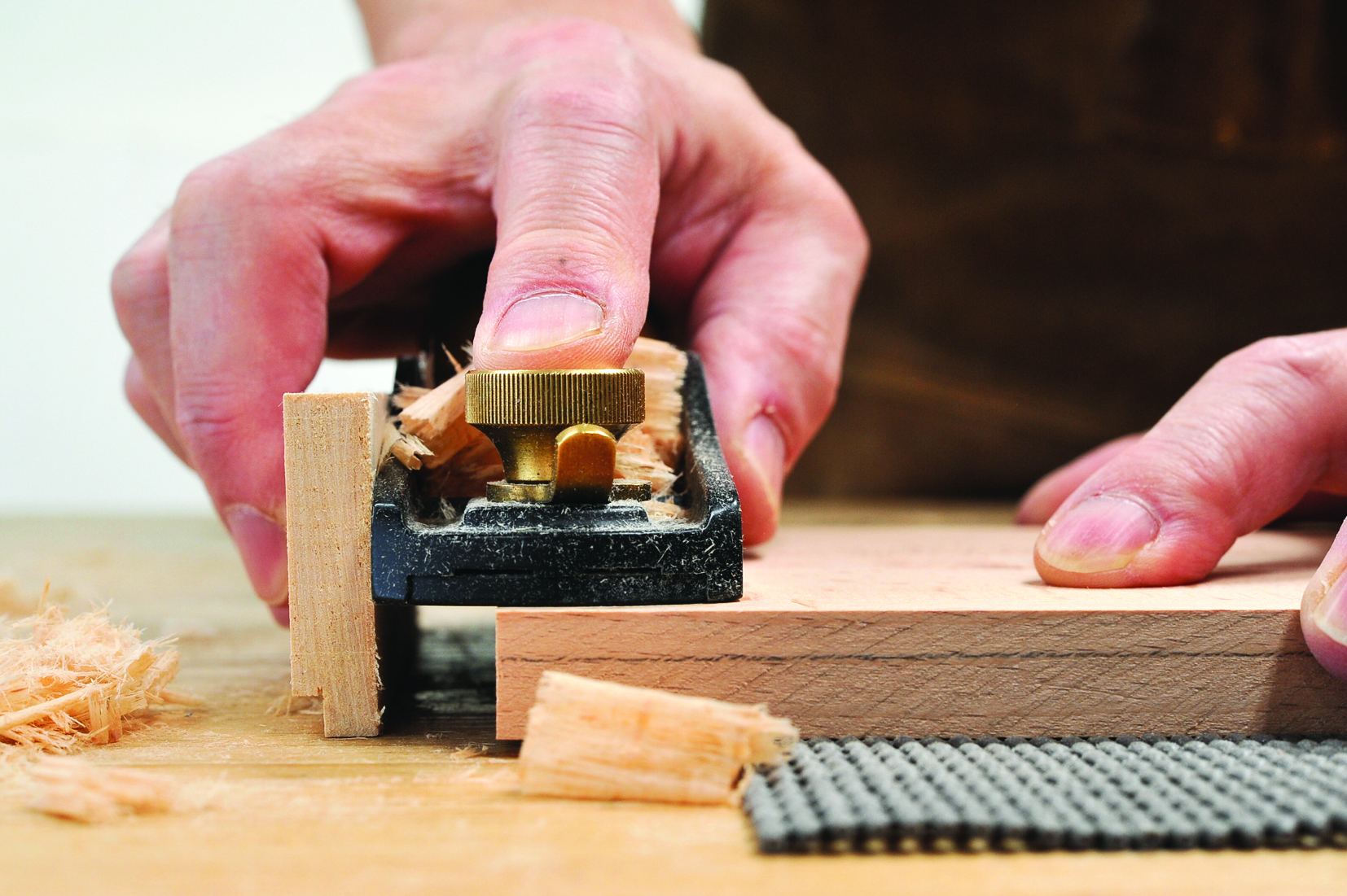 Person planing wood with hand tool.