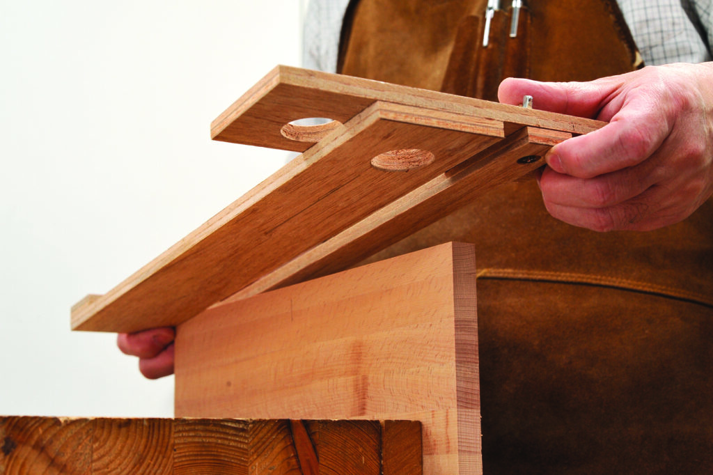 Carpenter assembling wooden joinery piece with dowels