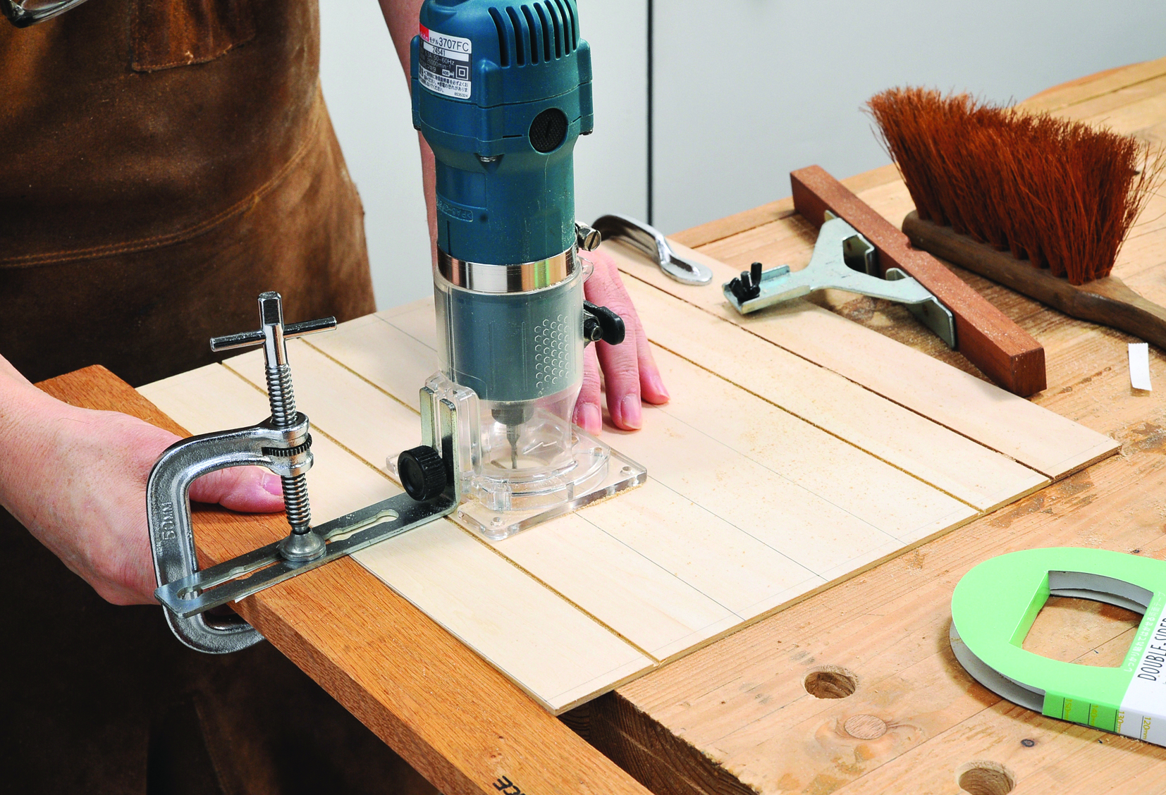 Person using router on wooden board with tools.