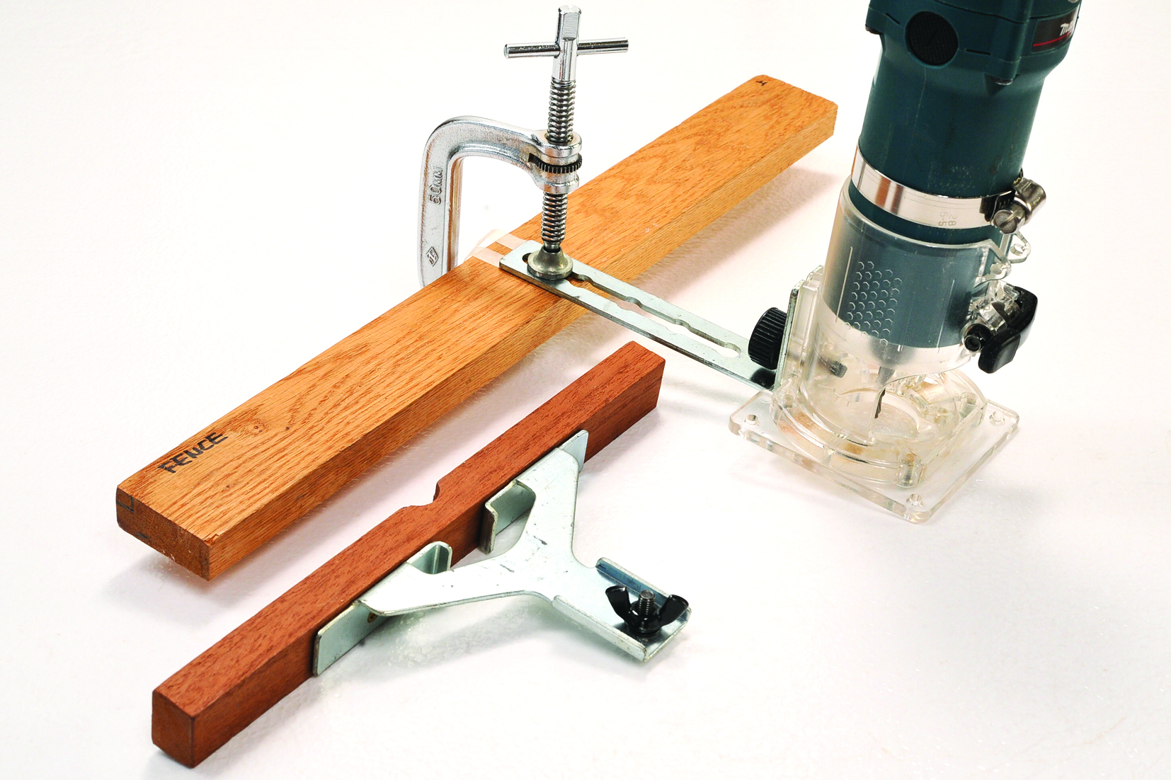 Router with guide on a wooden board.