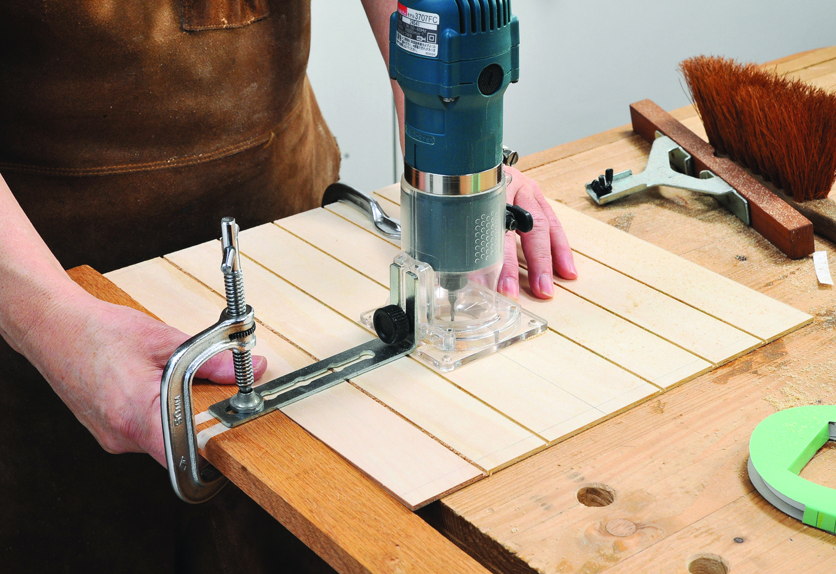 Woodworker using router on wooden board
