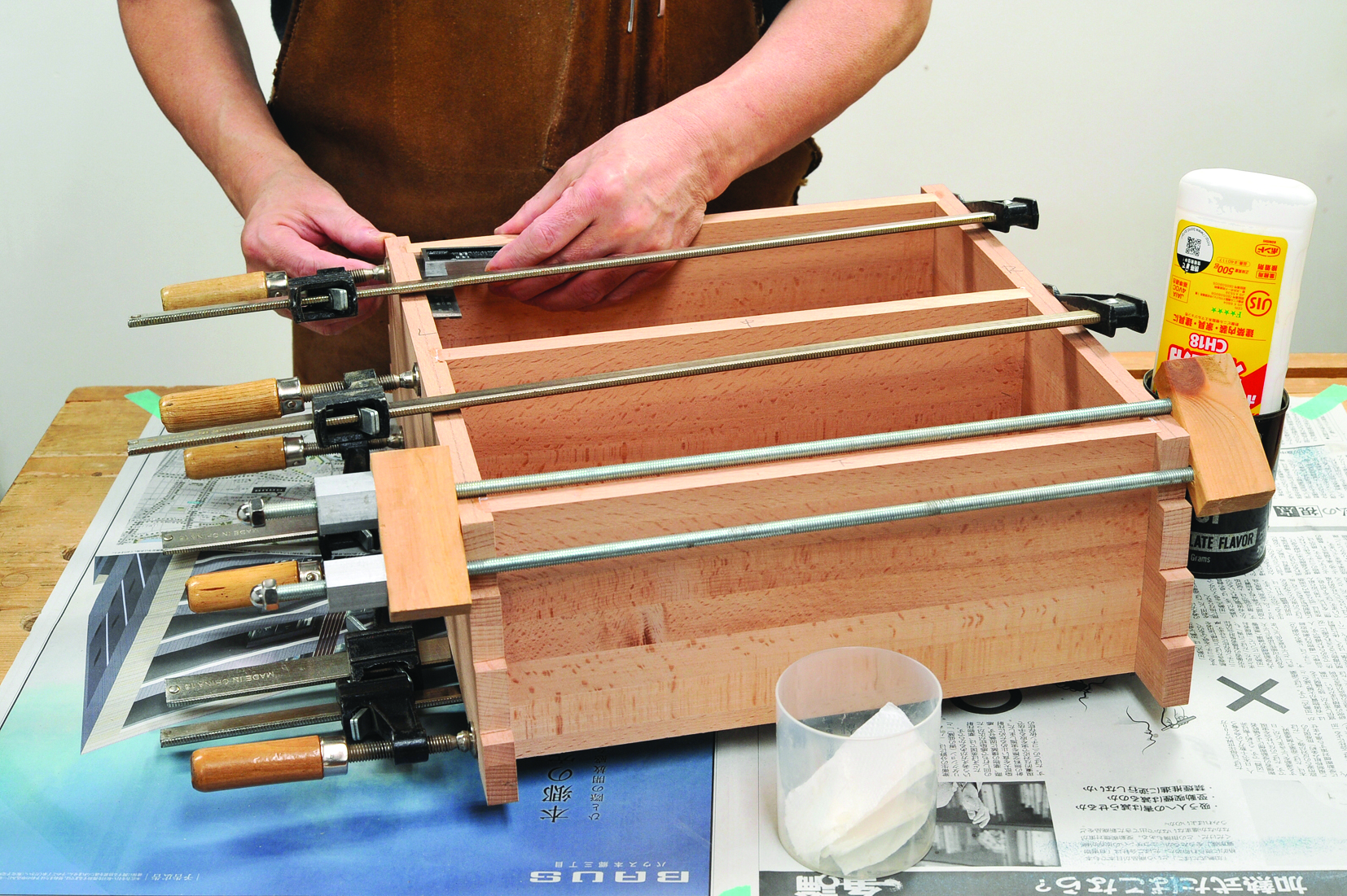 Person assembling wooden box with clamps and glue.
