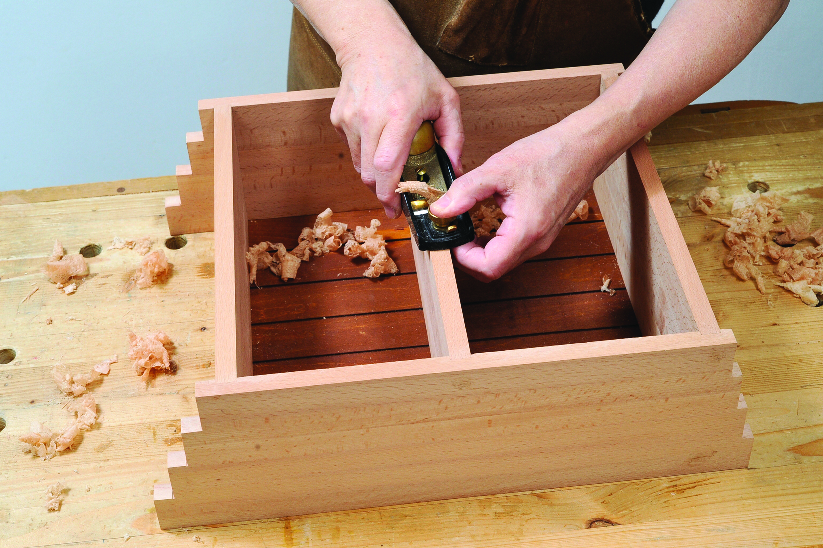 Woodworker using hand plane on wooden joint