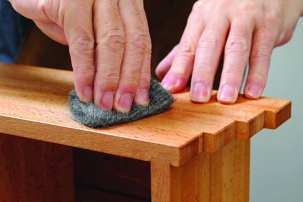 Sanding wooden furniture with steel wool pad
