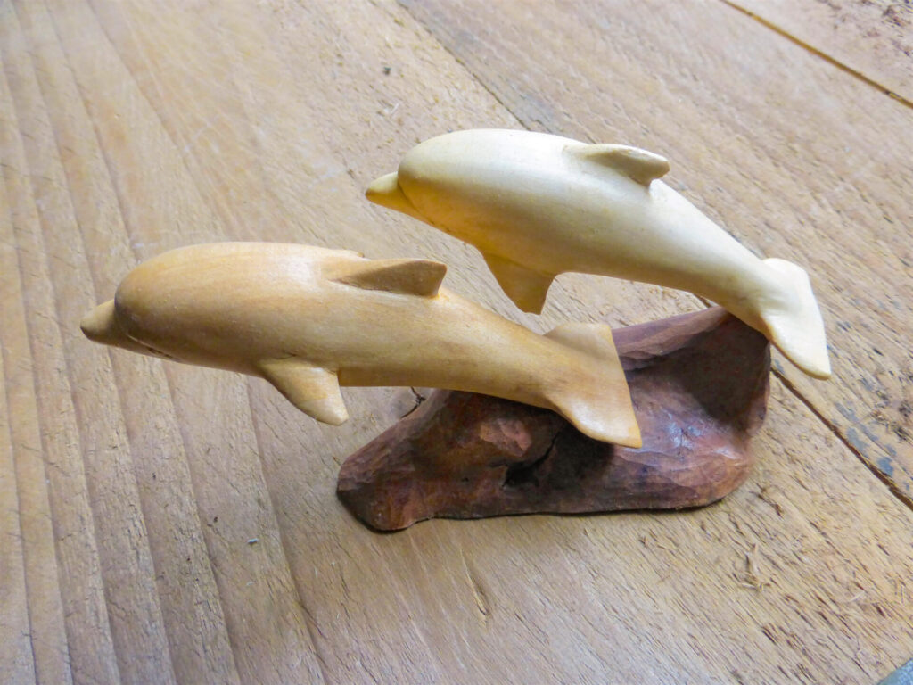 Wooden dolphin sculpture on wooden surface