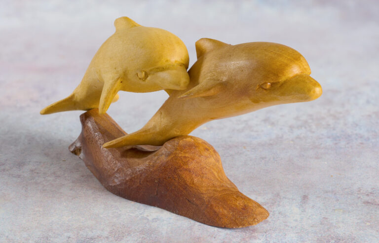 Wooden sculpture of two dolphins on a wave