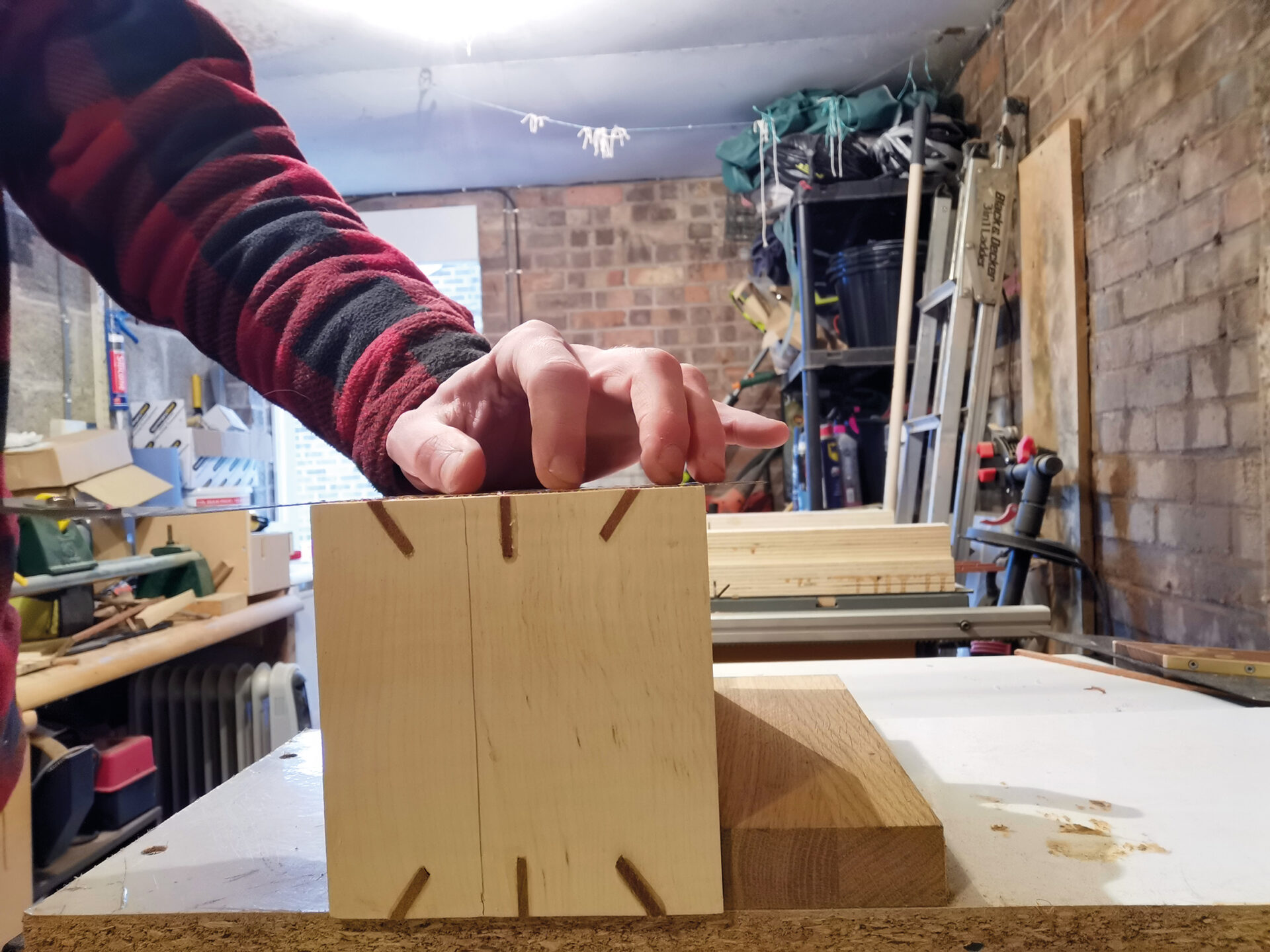 Person assembling wooden box in workshop.