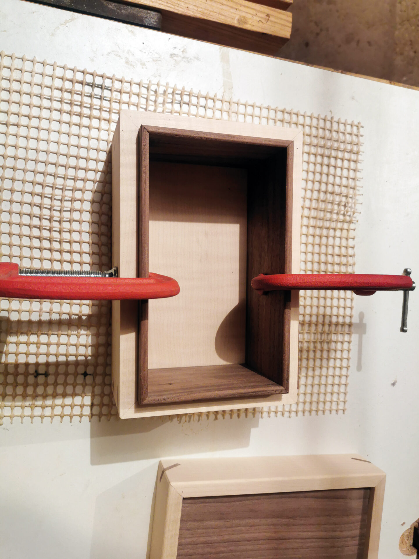 Wooden box clamped during construction on workbench.