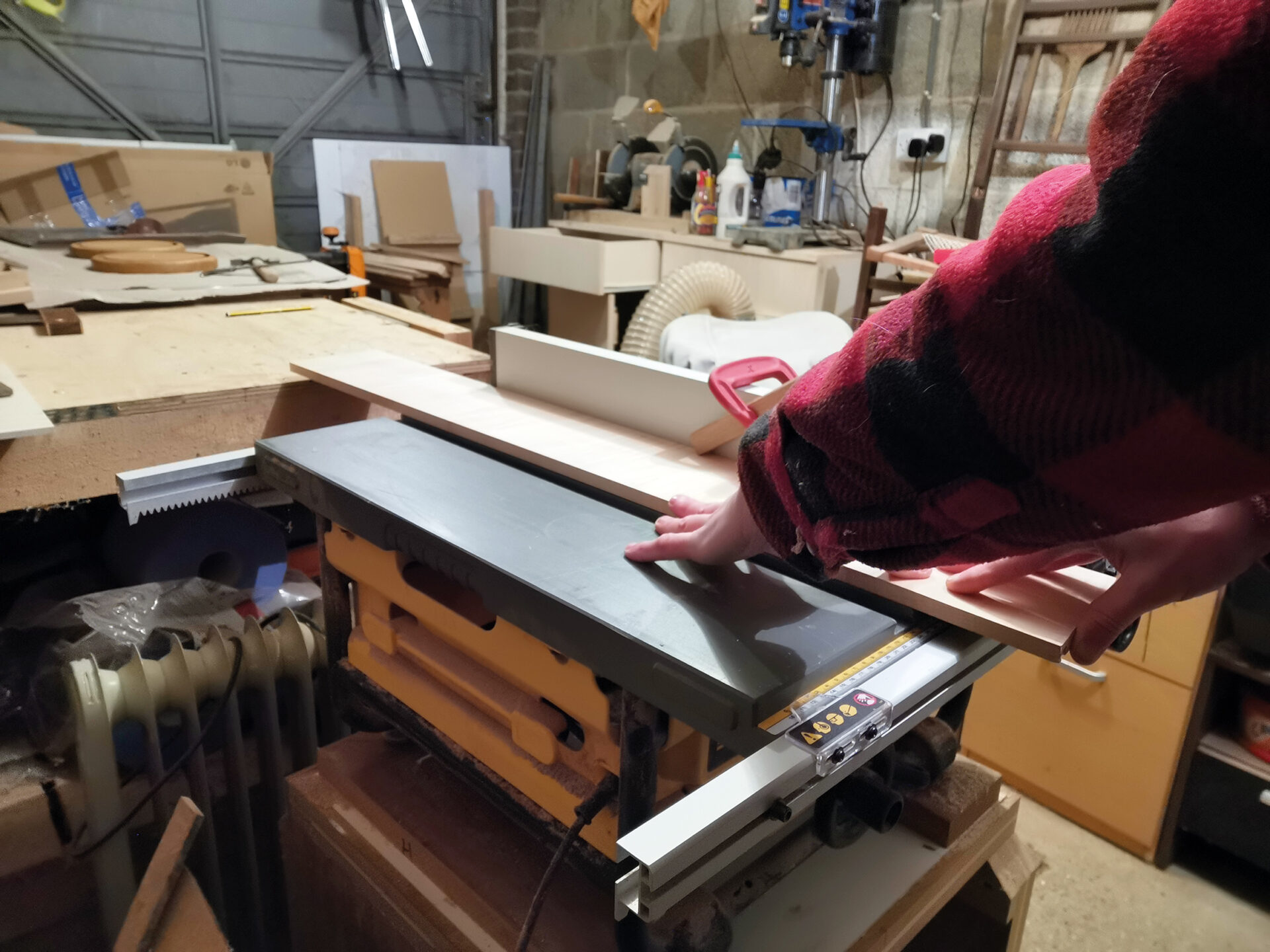 Person operating wood planer in workshop.