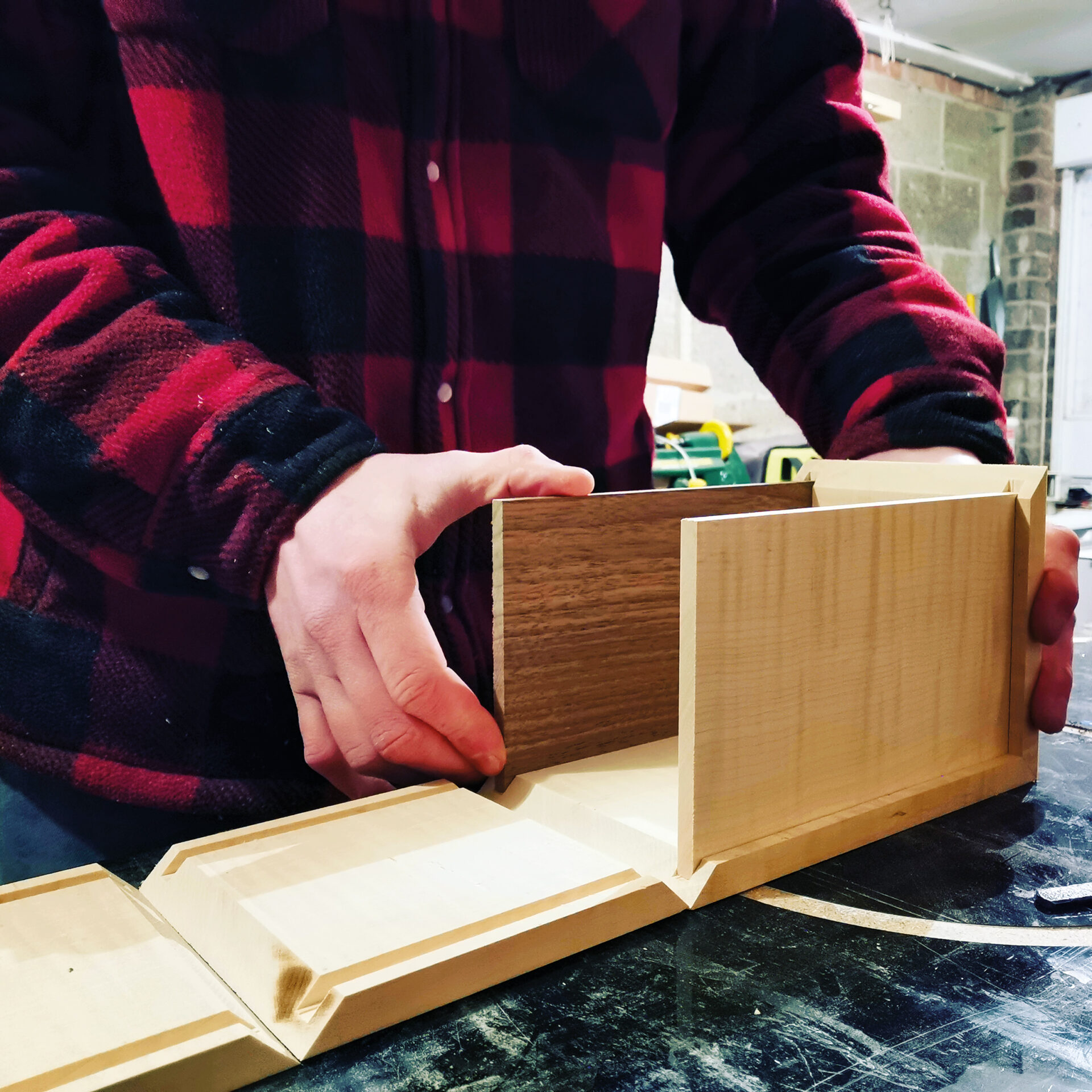 Person assembling wooden parts in workshop.