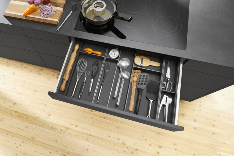 Kitchen drawer with assorted utensils and chopping board.