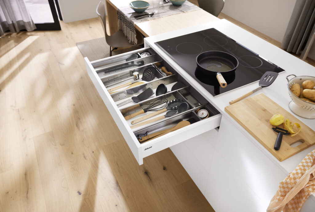 Modern kitchen with open utensil drawer and hob.