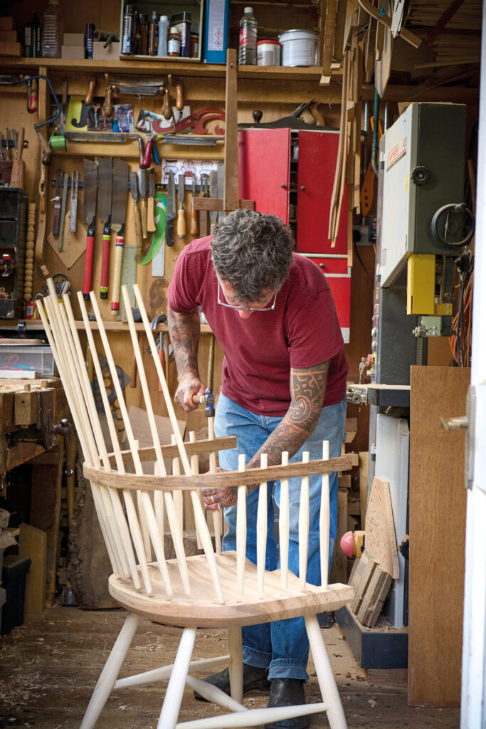 Carpenter working on wooden chair in workshop.