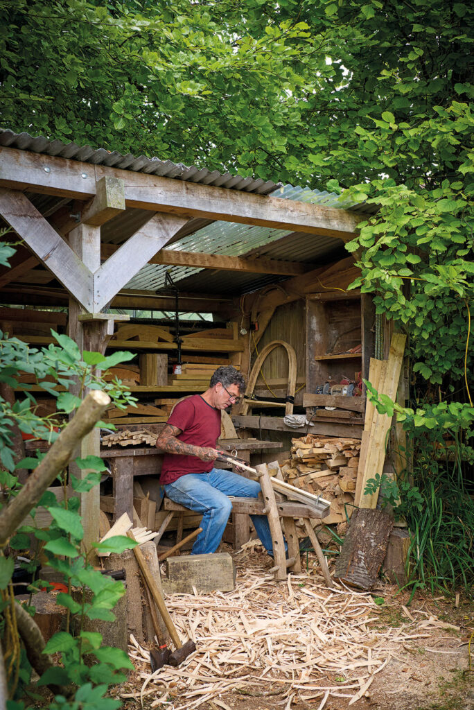 Man carving wood in garden workshop.