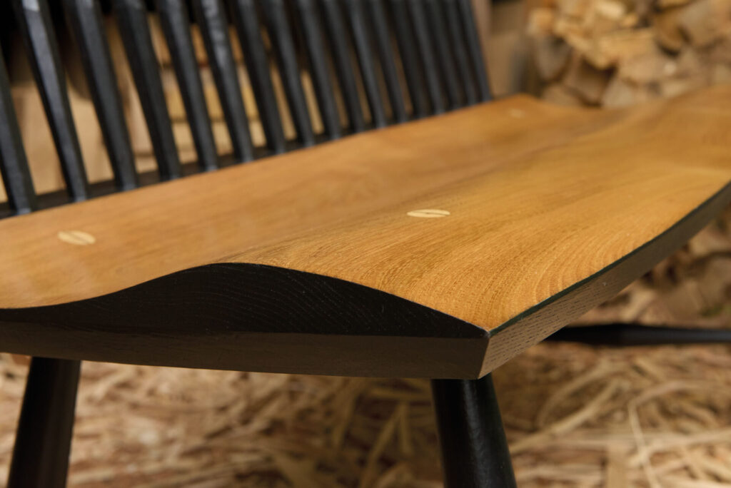 Close-up of wooden bench with black spindles.