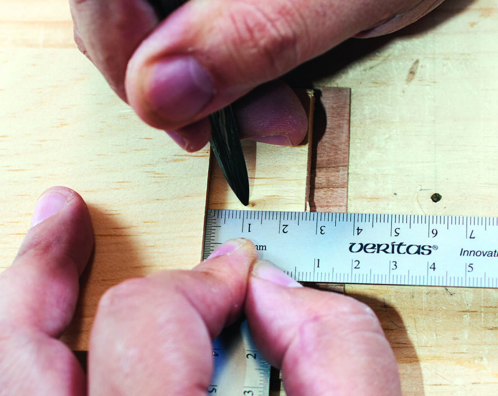 Hands measuring wood with ruler and pencil.