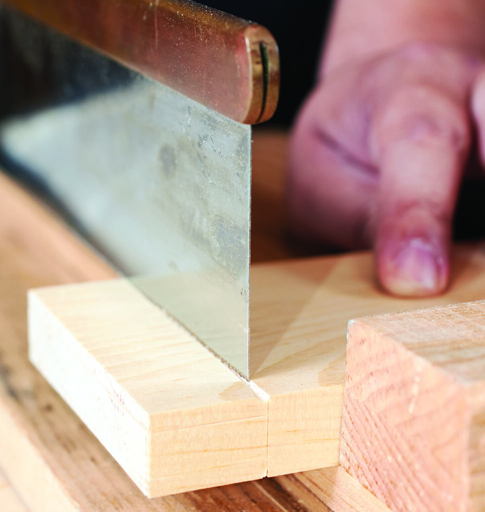 Close-up of hand saw cutting wooden plank.