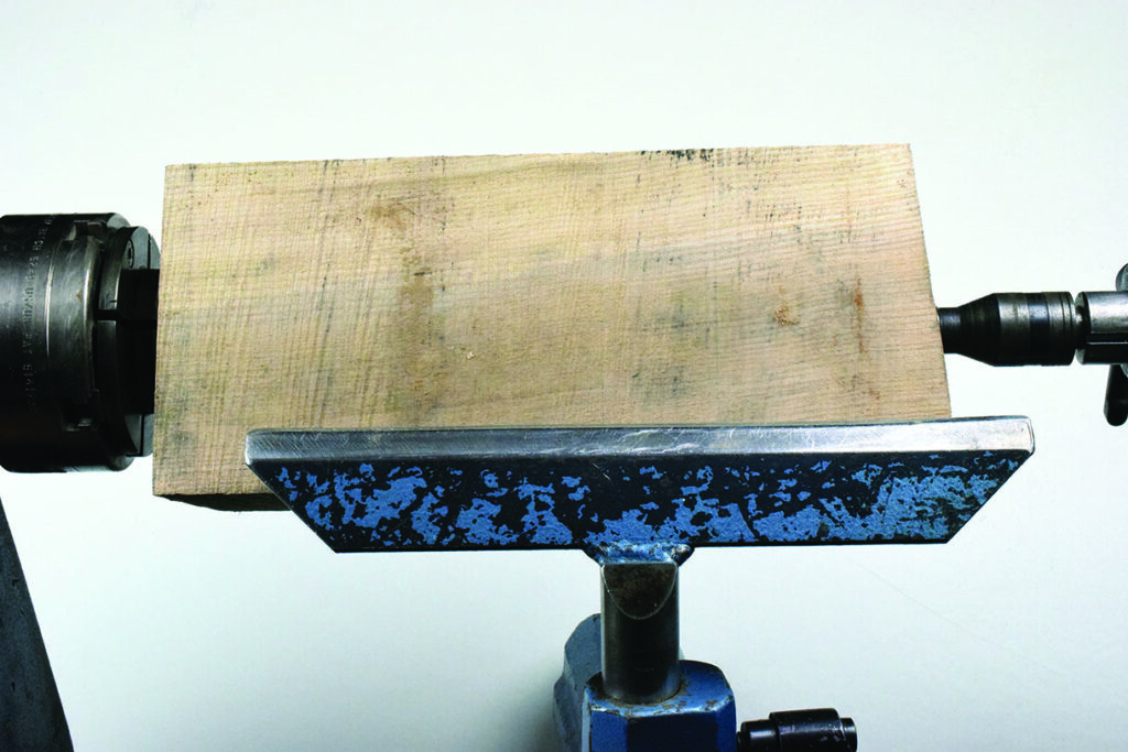 Wood block clamped in metal lathe.