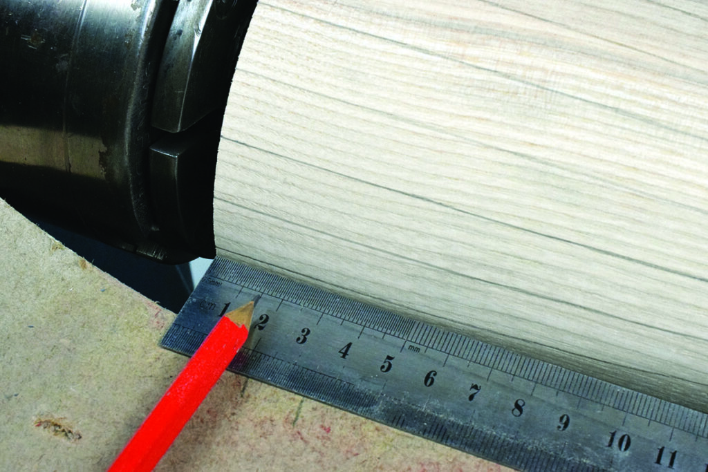 Red pencil and ruler measuring wood surface