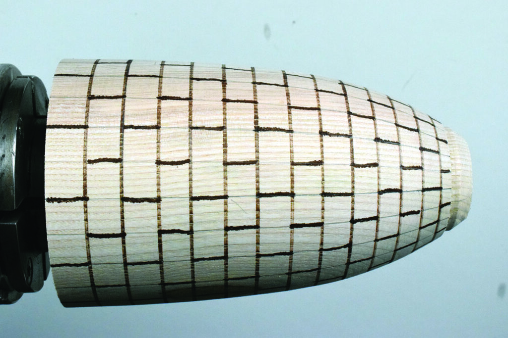 Wooden pattern with grid lines on a lathe.