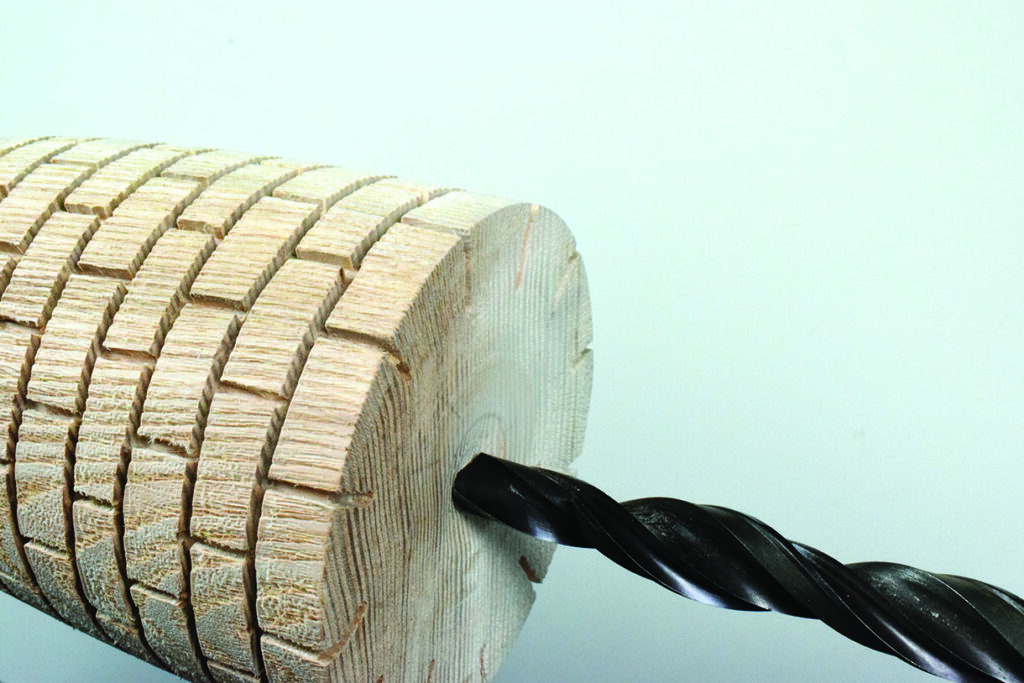 Drill bit entering segmented wooden log end.