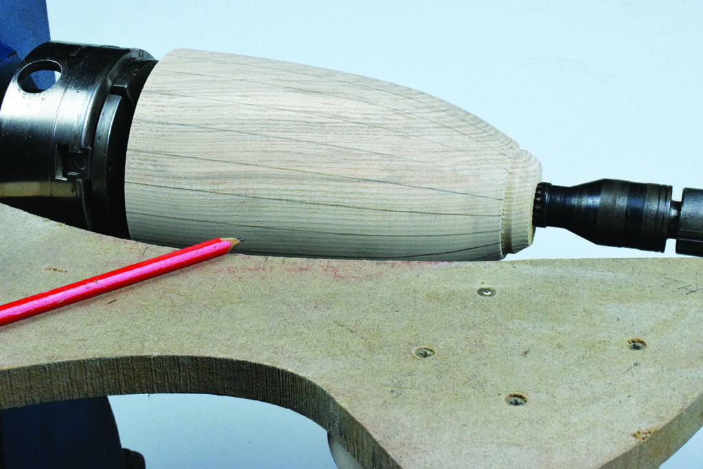 Woodturning with lathe and red pencil guide marks.