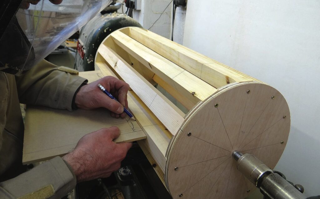 Person sketching near wooden drum structure