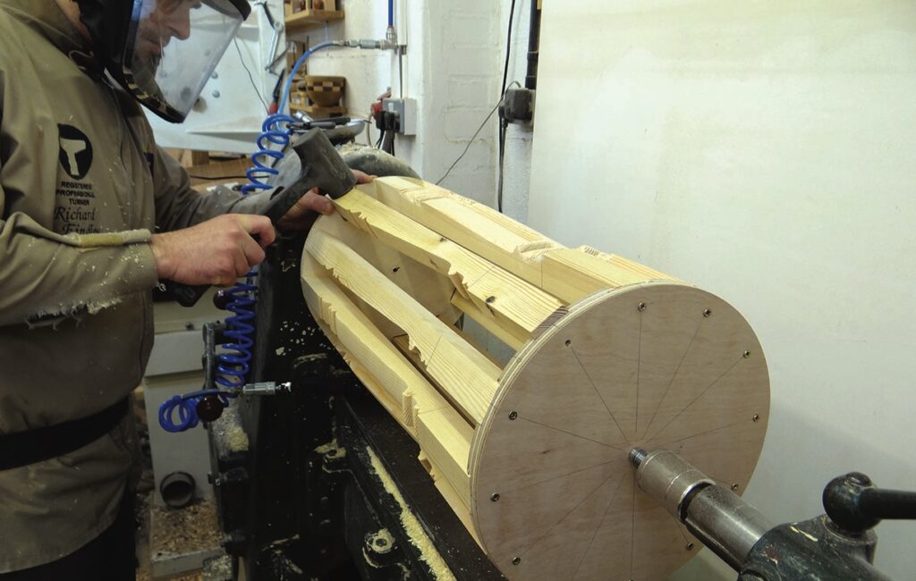 Woodturner shaping wooden cylinder on lathe machine.