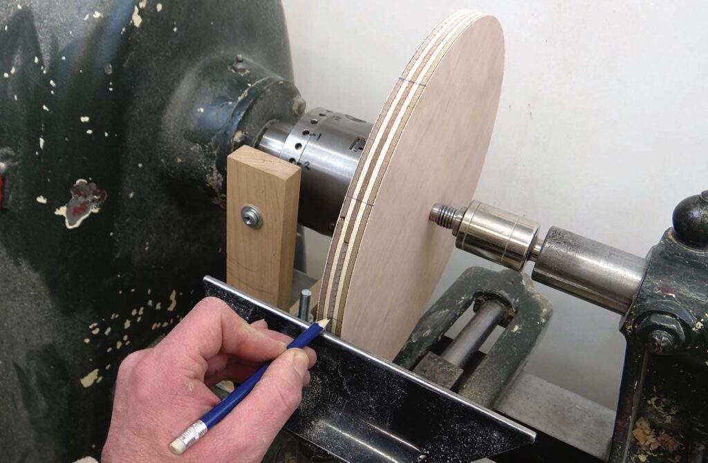 Person marking wood on lathe with pencil.