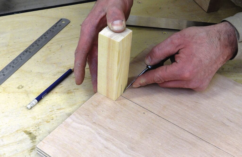 Person marking wood joint with awl tool
