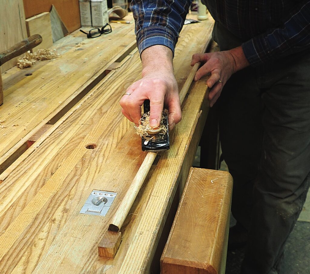 Man using hand plane on wooden workbench