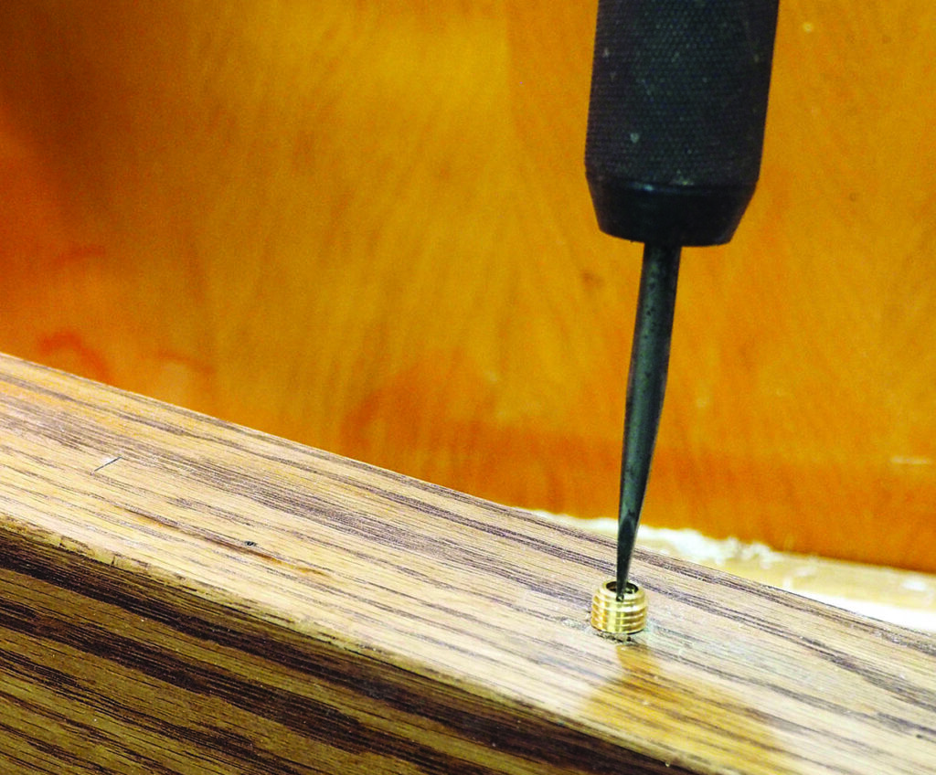 Drill installing threaded insert into wood surface.