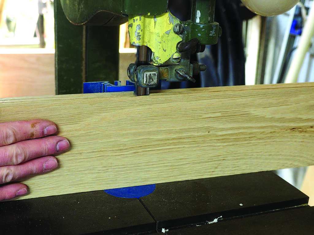 Wood being cut with a bandsaw in workshop.