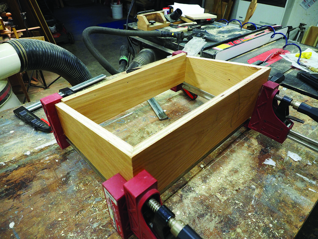 Wooden box clamped on a workshop table.