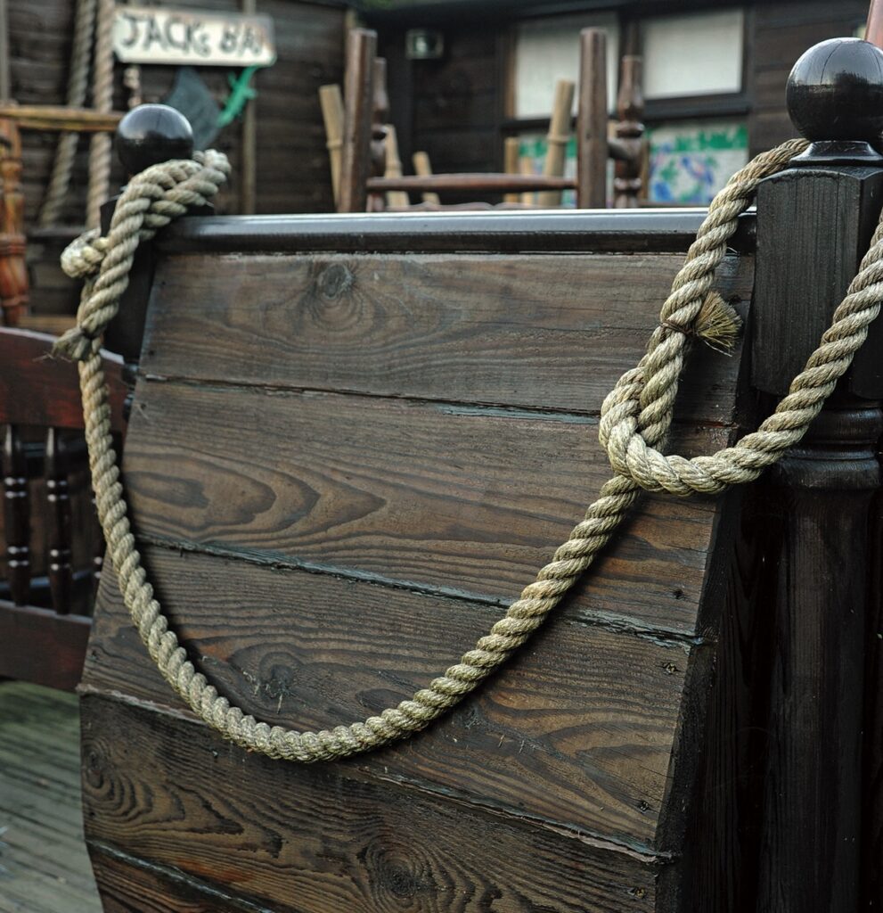 Rope tied on wooden ship deck railing.