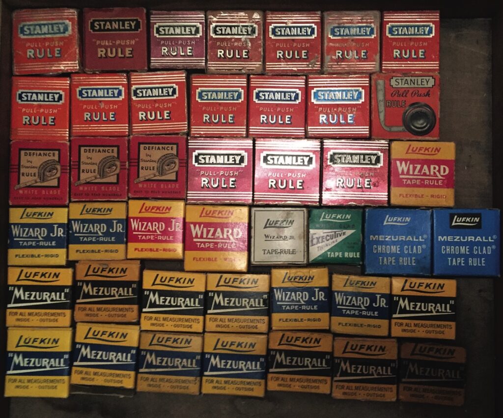 Collection of vintage tape measure boxes displayed.