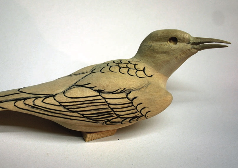 Carved wooden bird sculpture with etched details.
