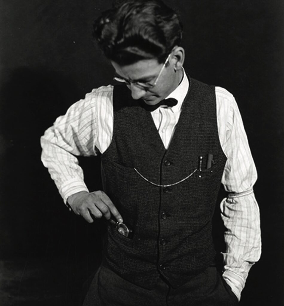 Man with glasses and waistcoat checking pocket watch.