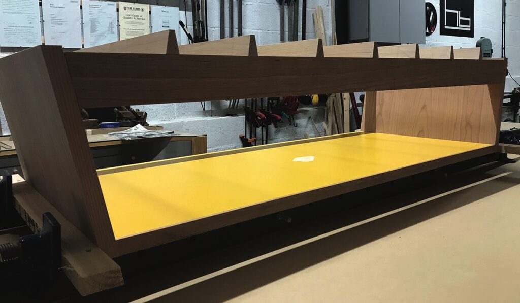 Wooden and yellow shelving unit under construction in workshop.