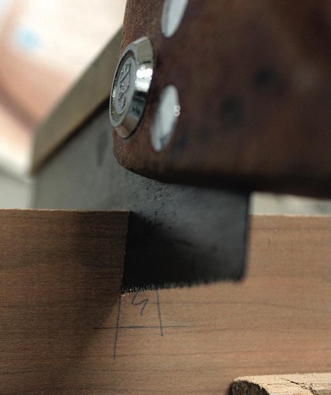 Close-up of saw cutting through wooden board.