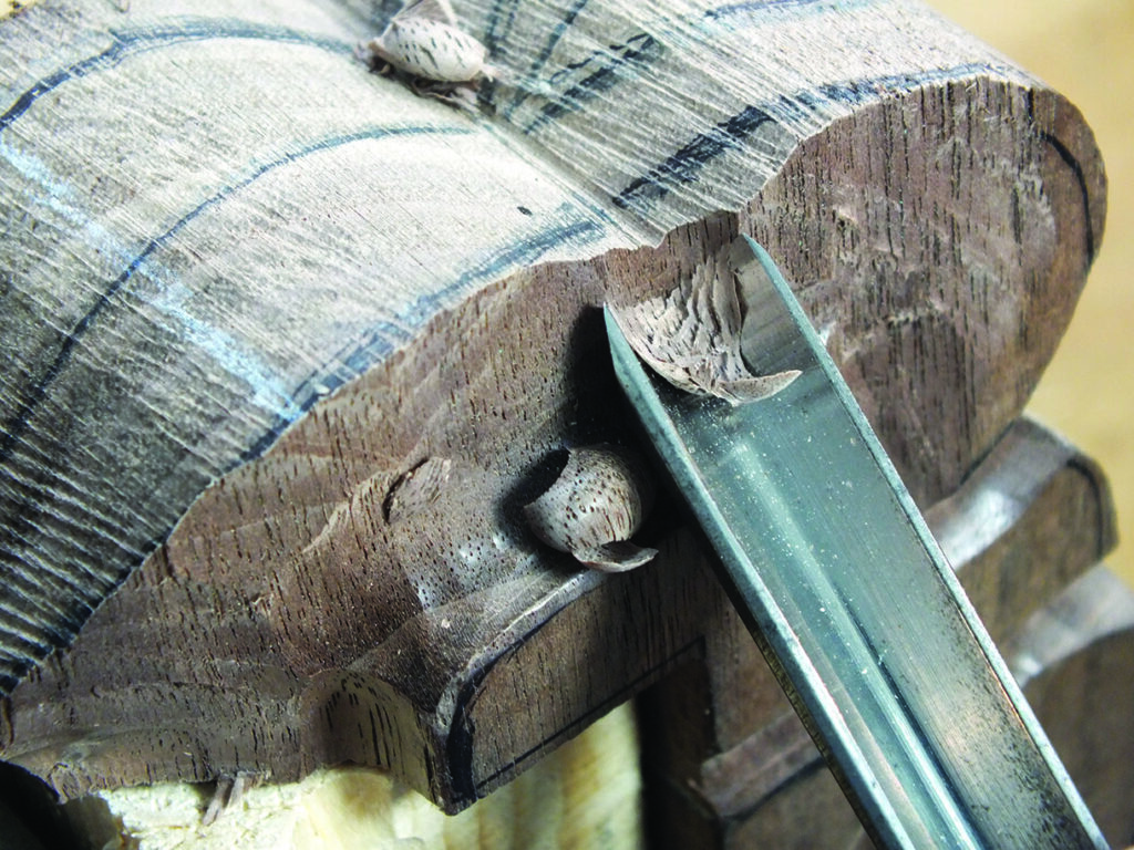 Chisel carving detailed wooden sculpture.