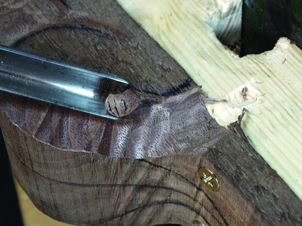 Chisel carving intricate wood detail.