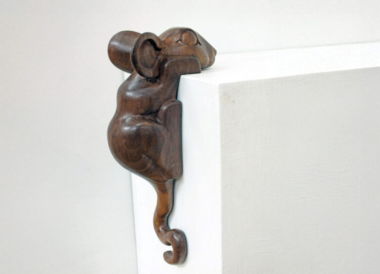 Wooden mouse sculpture hanging over edge