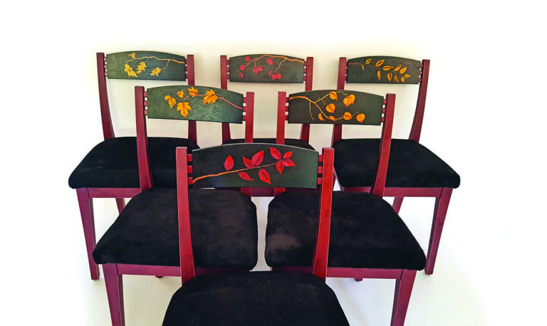 Colourful chairs with leaf designs on backs.