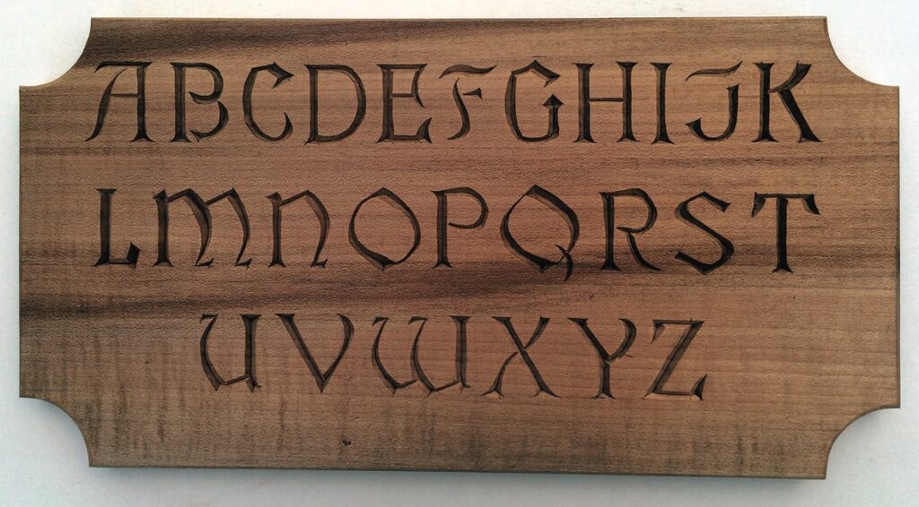Carved alphabet letters on wooden plaque.
