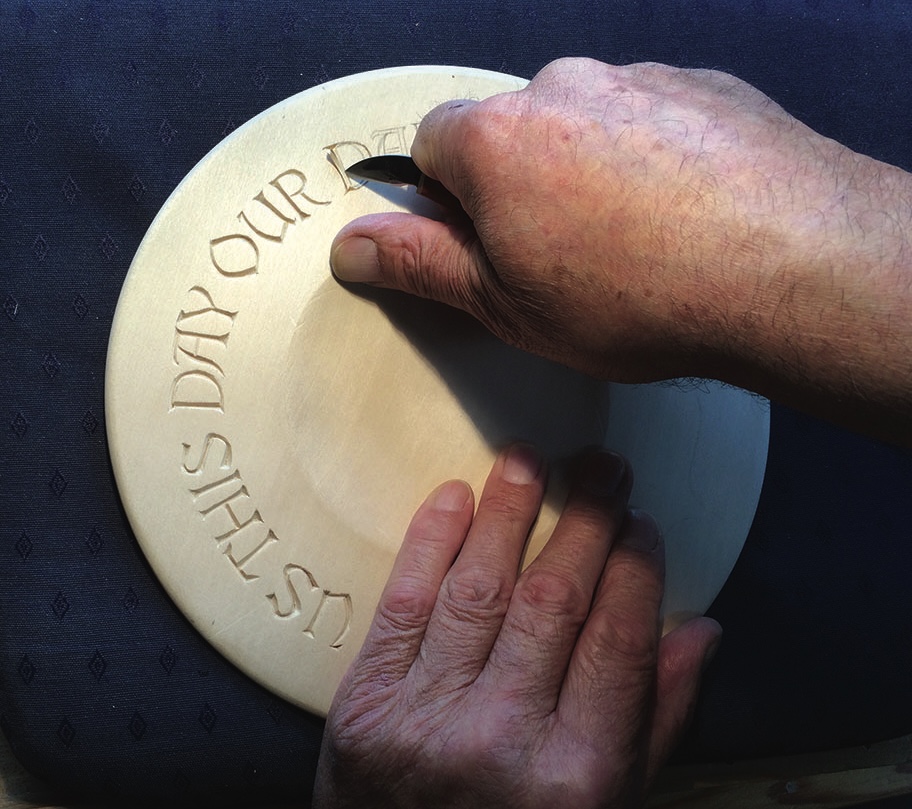 Hand carving text into a wooden plaque.