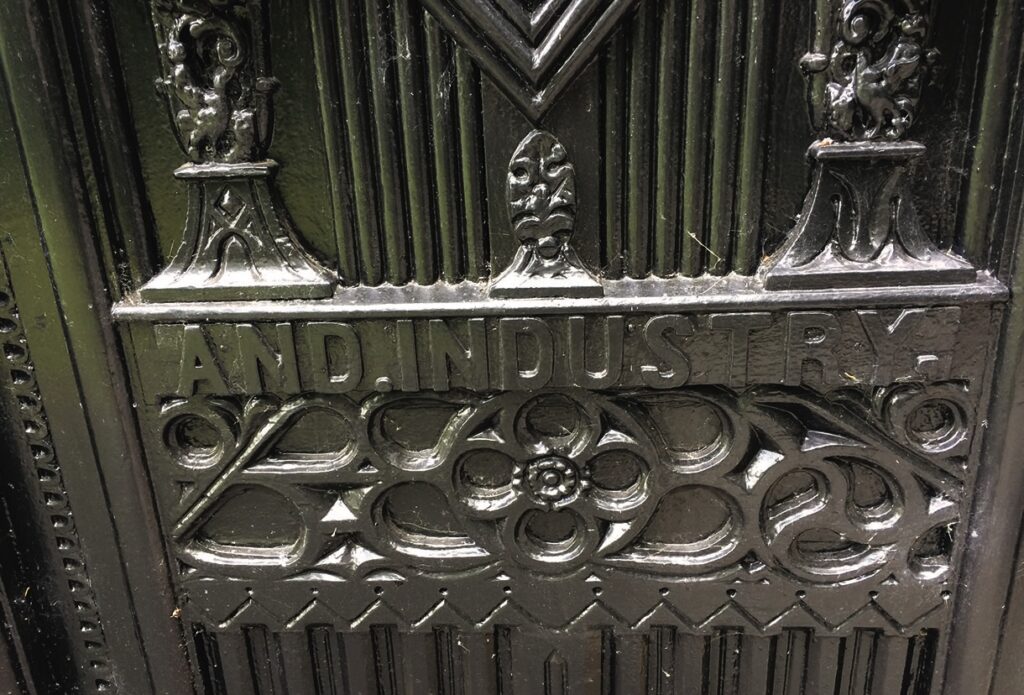 Ornate metal plaque with 'AND INDUSTRY' inscription