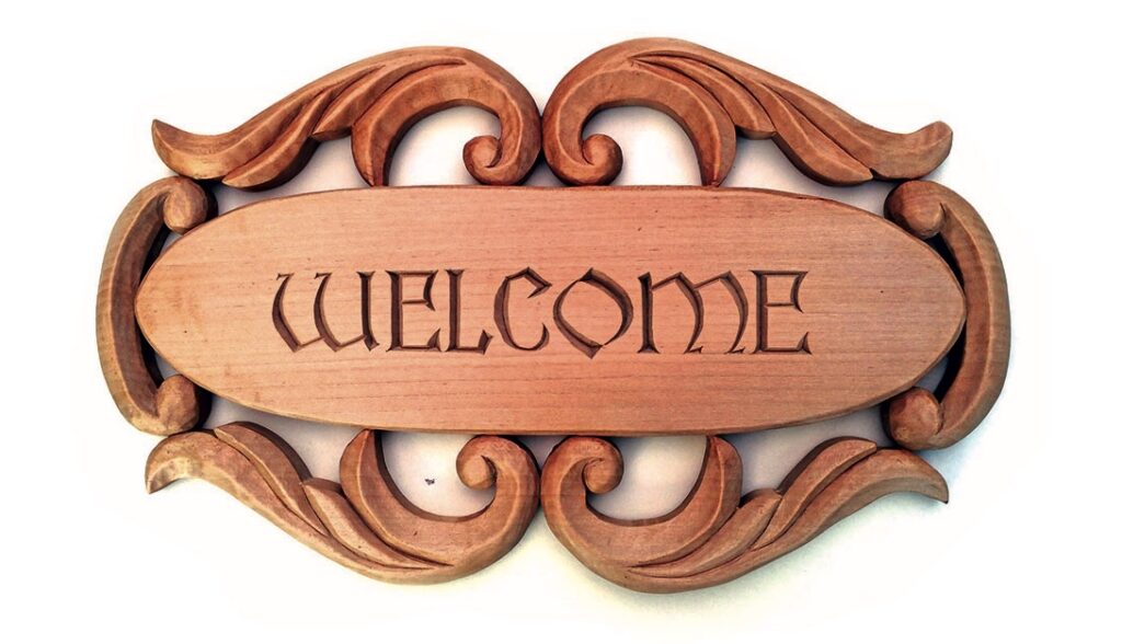 Wooden welcome sign with ornate carvings.