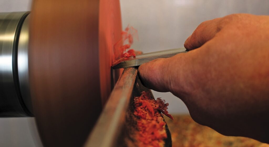 Woodturning with tool shaping spinning wood piece.